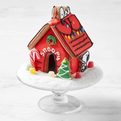 a gingerbread house decorated with icing and decorations on a cake plate for christmas