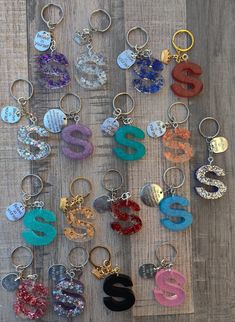 many different colored key chains on a wooden surface with letters and numbers attached to them