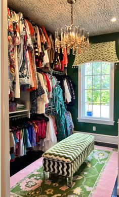 the closet is full of clothes and chandelier hanging from it's ceiling