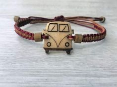 a bracelet with a bus charm on it sitting on top of a white table next to a brown cord