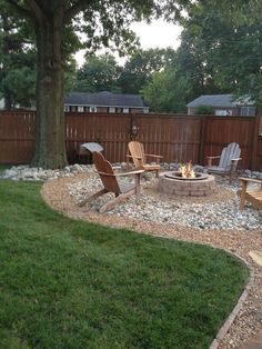 an outdoor fire pit surrounded by lawn chairs and rocks in the middle of a yard