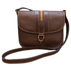 This vintage GUCCI Web equestrian crossbody bag is crafted of pigskin leather in brown featuring gold toned hardware and decorated with a brown/yellow stripe. Front magnetic snap closure opens to a brown nubuck leather interior featuring two open and one zippered compartments and a zippered pocket for easy access. This Gucci is the perfect compact crossbody for keeping your small accessories well organized. Made in Italy. Measures approximately 8 x 6.5 x 3.5 inches Strap Drop 21 inches. Comes wi Mario Testino, Pig Skin, Yellow Stripes, Nubuck Leather, 1980s Vintage, Small Accessories, Leather Interior, Fashion Handbags, Vintage Gucci