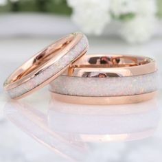 two gold wedding bands with white opal inlays are on a marble surface