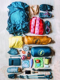 the contents of a backpack laid out on a wooden surface with hiking equipment and water bottles