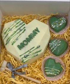 a box filled with green decorated cookies in the shape of heart and mom written on it