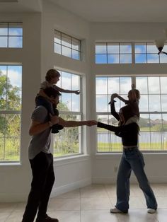 three people standing in front of large windows with their arms around each other as they hold hands