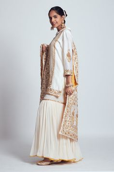 Daisy ivory straight short kurta with placement gota patti and dabka zardozi worked floral motifs. Comes with gharara and jaal pattern dupatta enhanced with mustard pure banarasi booti fabric at the back.
Component: 3
Embroidered
Neckline: Round
Sleeve Length: Three Quarter
Fabric: Kurta and Dupatta: Chanderi silk; Gharara: Georgette; Banarasi
Color: White
Button placket
Side slits
 - Aza Fashions Silk Gharara, Bridal Shower Props, Kurta And Dupatta, Zardozi Work, White Kurta, Boutique Dress Designs, Embroidered Neckline, Party Wear Dresses, Bridal Outfits