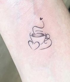 a small tattoo on the wrist of a woman with a cup of coffee in her hand