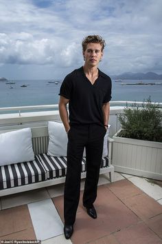 a man standing on top of a balcony next to a black and white striped couch