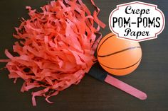 an orange ball and some red streamers on a table with the words crepe pom - poms paper