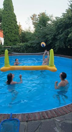 three people playing volleyball in a pool with an inflatable volley ball set on the side