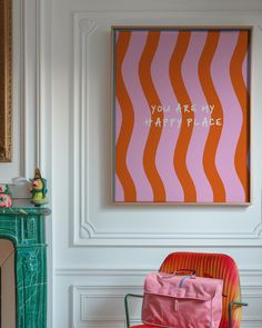 an orange and pink chair sitting in front of a painting