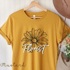 Cute Florist T-shirt! This will be a great gift for future florist, or for current florists team T-shirt! This t-shirt is everything you've dreamed of and more. It feels soft and lightweight, with the right amount of stretch. It's comfortable and flattering for all. * 100% combed and ring-spun cotton (Heather colors contain polyester) * Fabric weight: 4.2 oz/yd² (142 g/m²) * Pre-shrunk fabric * Side-seamed construction * Shoulder-to-shoulder taping * Blank product sourced from Guatemala, Nicarag Casual Yellow T-shirt As A Gift, Floral Print Graphic Tee T-shirt As Gift, Floral Print T-shirt For Spring Gift, Floral Print T-shirt As A Spring Gift, Floral Print T-shirt For Spring, Casual Floral Print T-shirt Gift, Casual Floral Print T-shirt For Gift, Casual Floral Print T-shirt As Gift, Spring Graphic Print T-shirt Gift