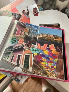 an open book with pictures on it sitting on top of a table next to a pile of books