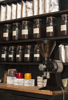 a coffee maker sitting on top of a wooden counter next to jars filled with coffee