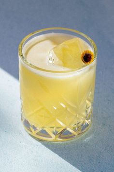 a glass filled with yellow liquid on top of a table