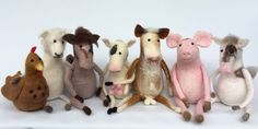 a group of stuffed animals sitting next to each other on a white surface with one animal in the middle