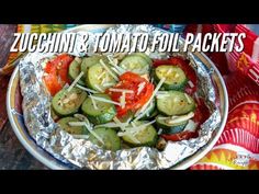 a metal pan filled with sliced cucumbers and tomato slices on top of tin foil