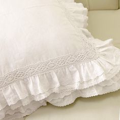 a close up of a pillow on a bed with white sheets and ruffles