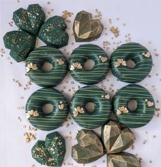 green donuts with gold sprinkles are arranged on a white surface next to other doughnuts