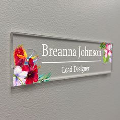 a glass sign with flowers on it that says,'breanna johnson lead designer '