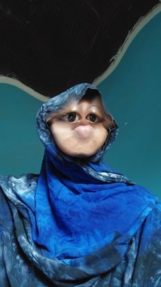 a woman with a blue scarf around her head and eyes looking up at the camera