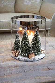 a glass candle holder with christmas trees in it on a table next to a couch