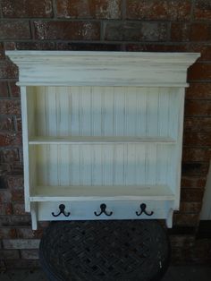 an old white book shelf with hooks on it