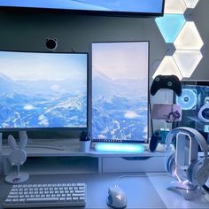 two computer monitors sitting on top of a desk next to a keyboard and headphones