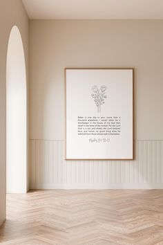 an empty room with a framed print on the wall and wood flooring in front of it