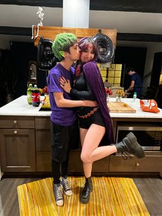 two people dressed as the joker and harley kissing in front of a kitchen counter top