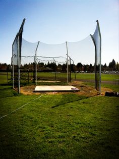 an empty batting cage in the middle of a field