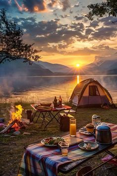 a table with food and drinks on it in front of a tent at the water's edge