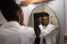 a woman is brushing her hair in front of a mirror