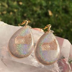 These holographic Teardrop geode earrings made from resin shift from clear gold to a beautiful sparkly rainbow. They are lightweight and won't bother your ears. Please be aware that resin is heat resistant up to 135 degrees. Wearing these earrings in extremely hot temperatures will cause them to be pliable. If this happens, simply place in a cooler location. I am not responsible for any damaged earrings due to extreme heat. Made by Katie Glover Resin Art by Katie 2020 Contact me on my Instagram Unique Gold Crystal Drop Earrings, Sparkling Dangle Teardrop Earrings Gift, Sparkling Teardrop Dangle Earrings As Gift, Hypoallergenic Resin Jewelry For Parties, Teardrop Sparkling Jewelry For Gift, Iridescent Nickel-free Crystal Earrings For Gift, Iridescent Sparkling Jewelry As Gift, Iridescent Sparkling Jewelry Gift, Sparkling Iridescent Jewelry As Gift