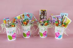 three buckets filled with candy and candies on top of a pink tablecloth