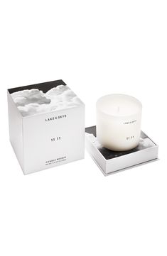 a white candle sitting on top of a box next to a black and white box