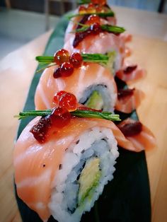 several sushi rolls are lined up on a green plate with sauce and garnishes