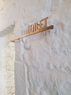 a wooden sign mounted to the side of a white wall that says iolff