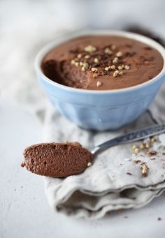 a bowl of chocolate pudding with a spoon next to it on a cloth and napkin