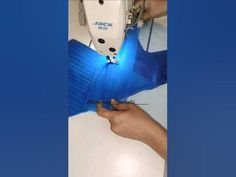 a person is using a sewing machine to sew something on a blue table cloth