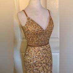 a gold dress with sequins on it sitting on a mannequin head