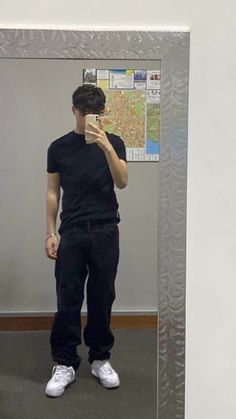 a man standing in front of a mirror taking a selfie with his cell phone