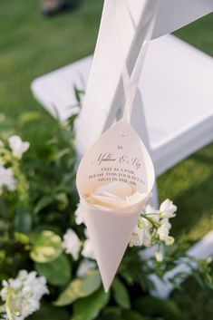 a wedding ceremony decoration with white flowers and paper cones hanging from the top of it