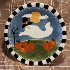 a plate decorated with pumpkins and a ghost in the sky on a tablecloth