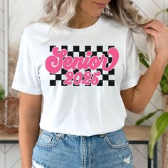 This cute checkered Senior 2025 shirt will be the perfect gift for your 2025 graduate! The Bella + Canvas 3001 tee is a unisex fit, meaning it's a bit slimmer through the midsection than a traditional men's tee, but not quite as fitted as a women's tee. Women should size down for a more fitted look and size up for a looser fit. .: 100% Airlume combed and ringspun cotton (fiber content may vary for different colors) .: Light fabric (4.2 oz/yd² (142 g/m .: Retail fit .: Runs true to size Please be sure to check the size chart photo. I recommend measuring one of your tees at home and comparing it with the size chart. I do not accept returns or exchanges due to a wrong size.  NO RETURNS, EXCHANGES, OR CANCELLATIONS Because my shirts are made to order and printed specific to your selection, I D Casual Shirt With Custom Print For Graduation, White Shirt With Letter Print For Graduation, White Graphic Print Shirt For College Events, White Tops For College Events In College Style, White Tops For College Events, Casual White Tops For College Events, High School Senior Gifts, 2025 Graduate, Senior Shirts