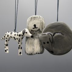 two ceramic animals hanging from strings on a gray background with black and white dots around them