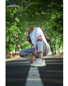 a young man crouching down on the side of a road