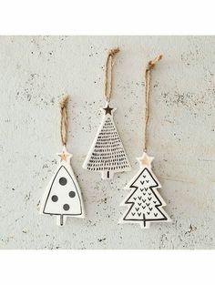 three wooden christmas trees hanging from twine strings on a white wall with black dots