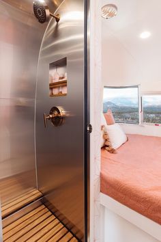 a bedroom with a metal door leading to a bed in the corner and a window